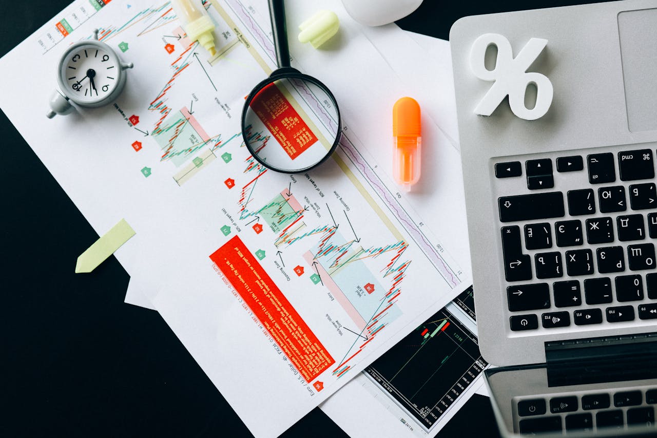 Home Top view of financial documents, charts, and laptop organized on a desk.